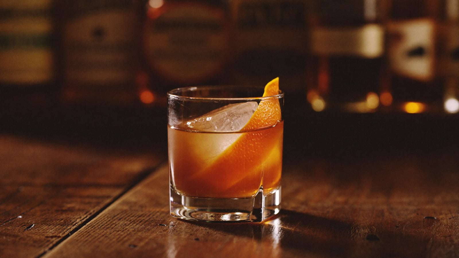 Un salon-bar chaleureux aux boiseries anciennes, longue rangée de bouteilles de whiskey
